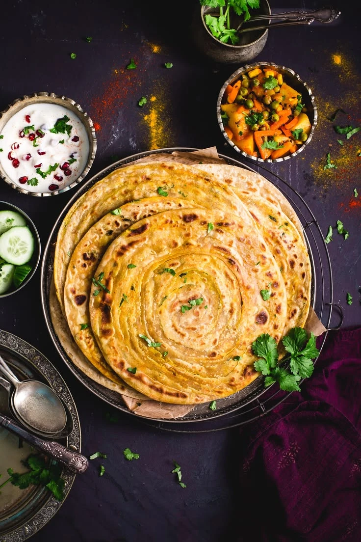 Layered lachha parathas served with vegetables and raita